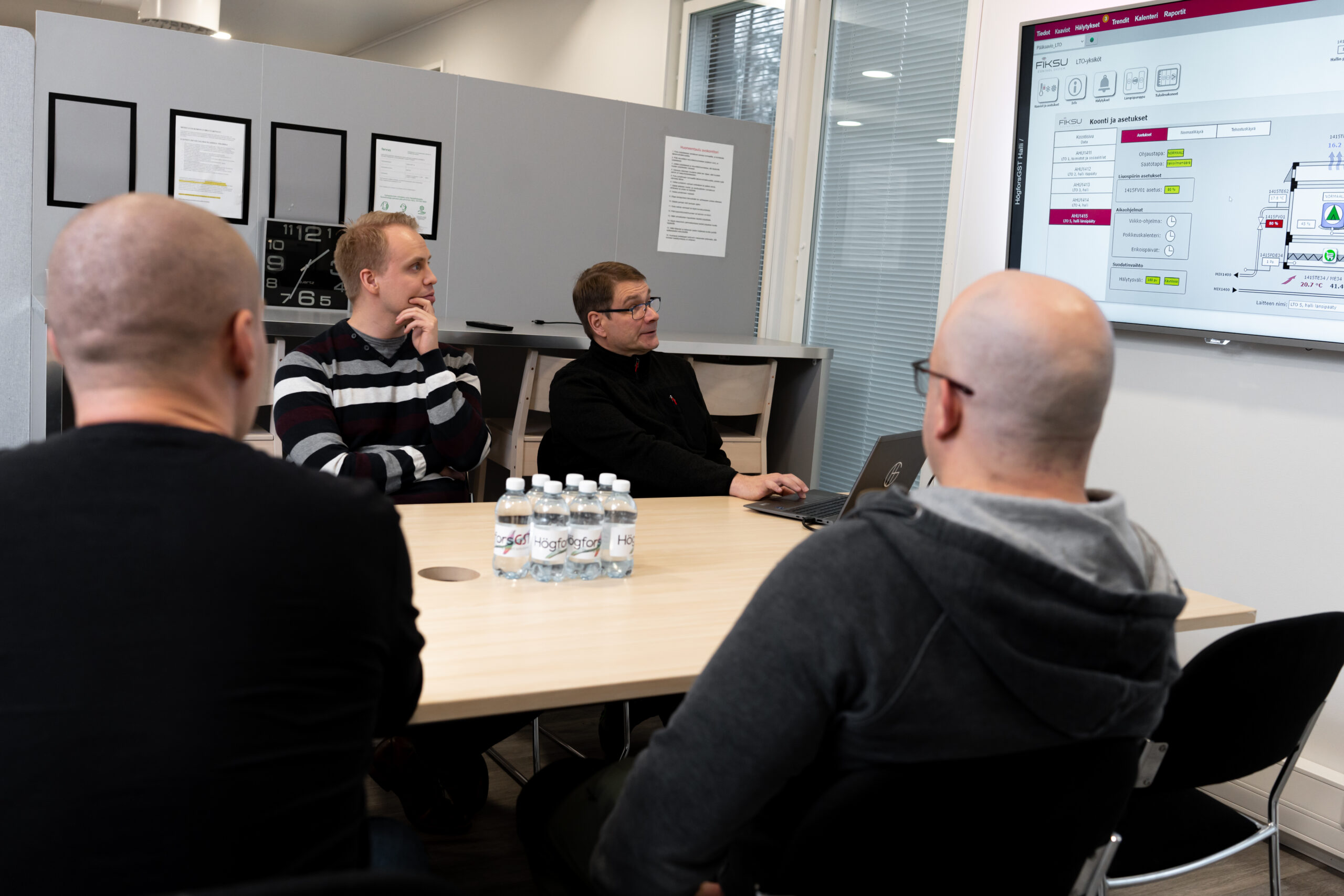 Four men in a meeting looking at HögforsGST's Fiksu Control system presented on a screen